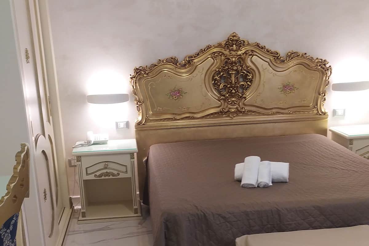 Una habitación de hotel con una cama grande, una mesita de noche, un tocador y un espejo.