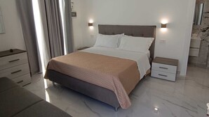 Een moderne slaapkamer met een groot bed, nachtkastjes en een bankje.