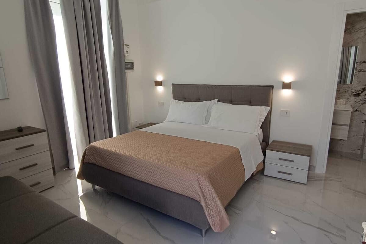 Un dormitorio moderno con una cama grande, mesitas de noche y un banco.