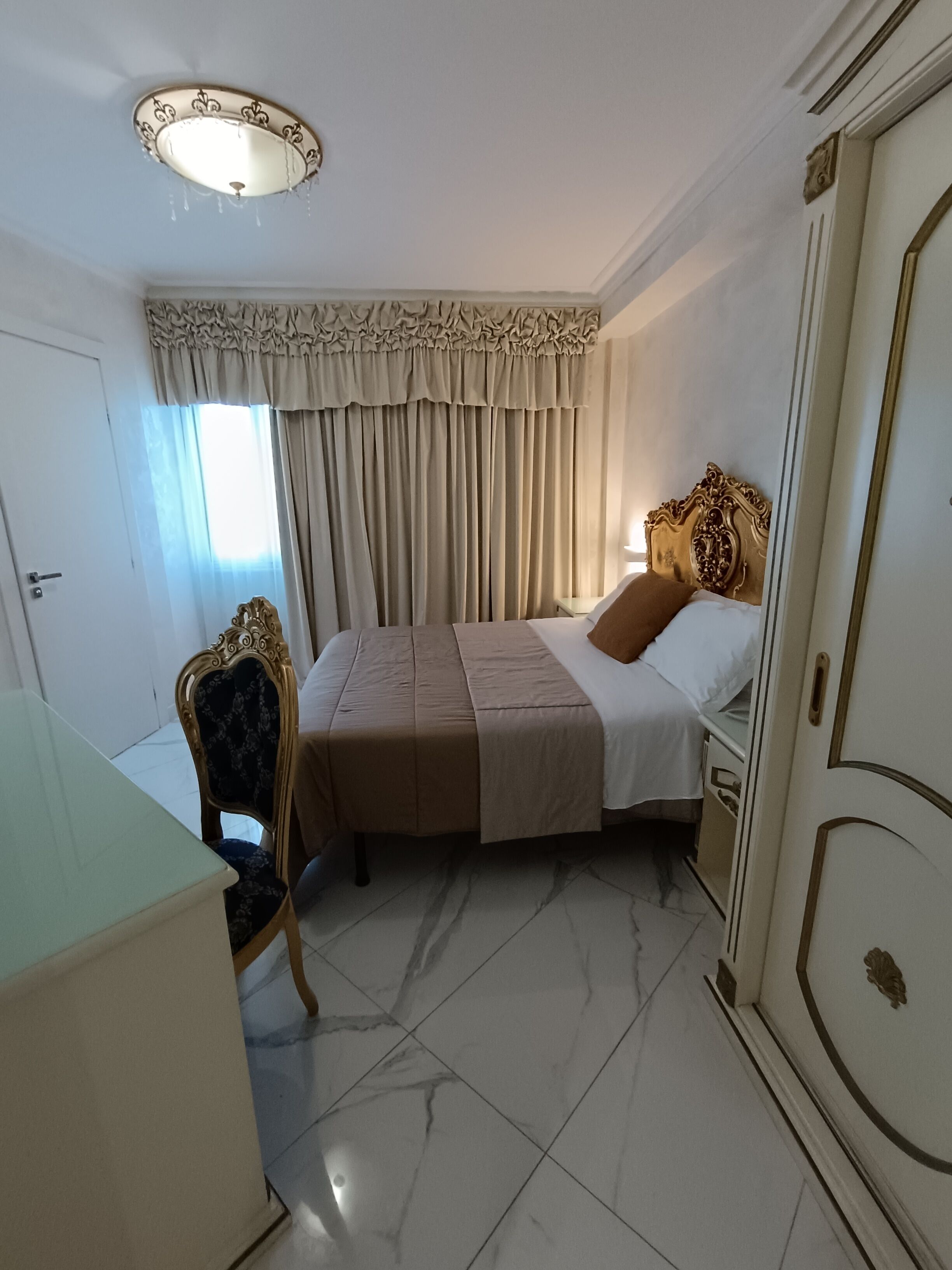 A hotel room with a bed, a desk, a chair, and a wardrobe.