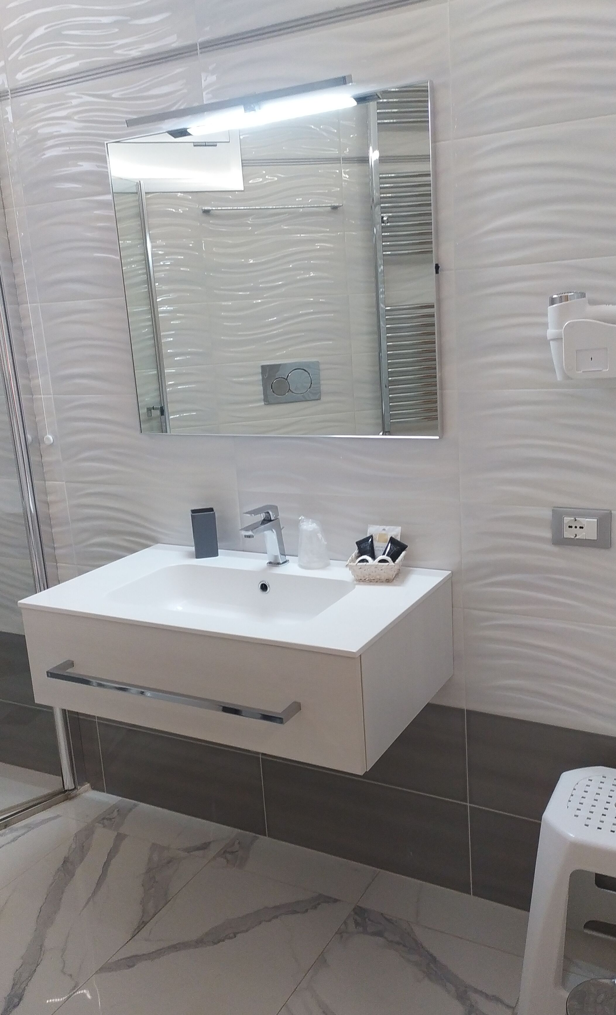 A bathroom with a white sink, a mirror, and a towel rack.