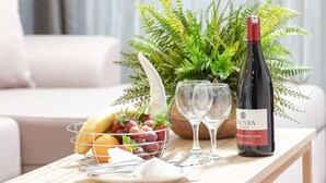 A dining table with a bottle of wine, glasses, a fruit basket, and a plant. - ROX Hotel Ankara (Ankara)