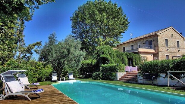 A swimming pool with lounge chairs, surrounded by greenery and a building with a tiled roof. - Beautiful private villa for 8 guests with WIFI, A/C, pool, TV, patio and panoramic view (Ostra)