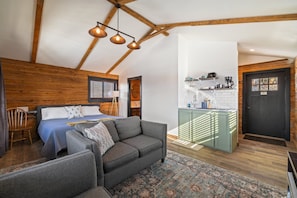 Cozy retreat with a comfortable bed, sofa, and kitchenette, perfect for a relaxing stay.