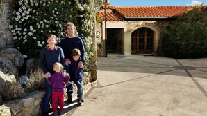 A family standing in front of a building with a stone facade and a tiled roof. - Large cottage in renovated Templar mas - panoramic view (Occitanie)