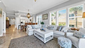 Un salon spacieux avec un canapé blanc, une table basse et un coin repas à l’arrière-plan.