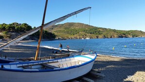 A boat on a sandy beach with a clear view of the sea and a hilly landscape in the background. - Small nest for 2 with 180 ° view on wooded hills in a cozy cottage (Occitanie,)