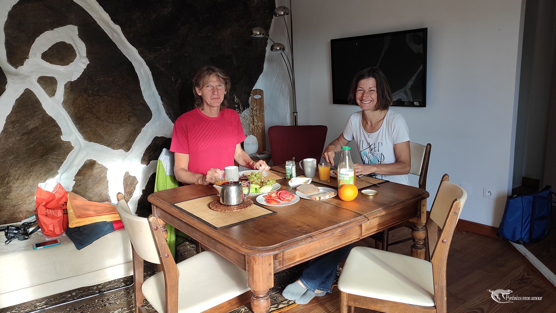 A dining table with two people seated, a bottle of Tropicana orange juice, and various food items.