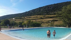 Una piscina con gente alrededor, rodeada por un paisaje montañoso.