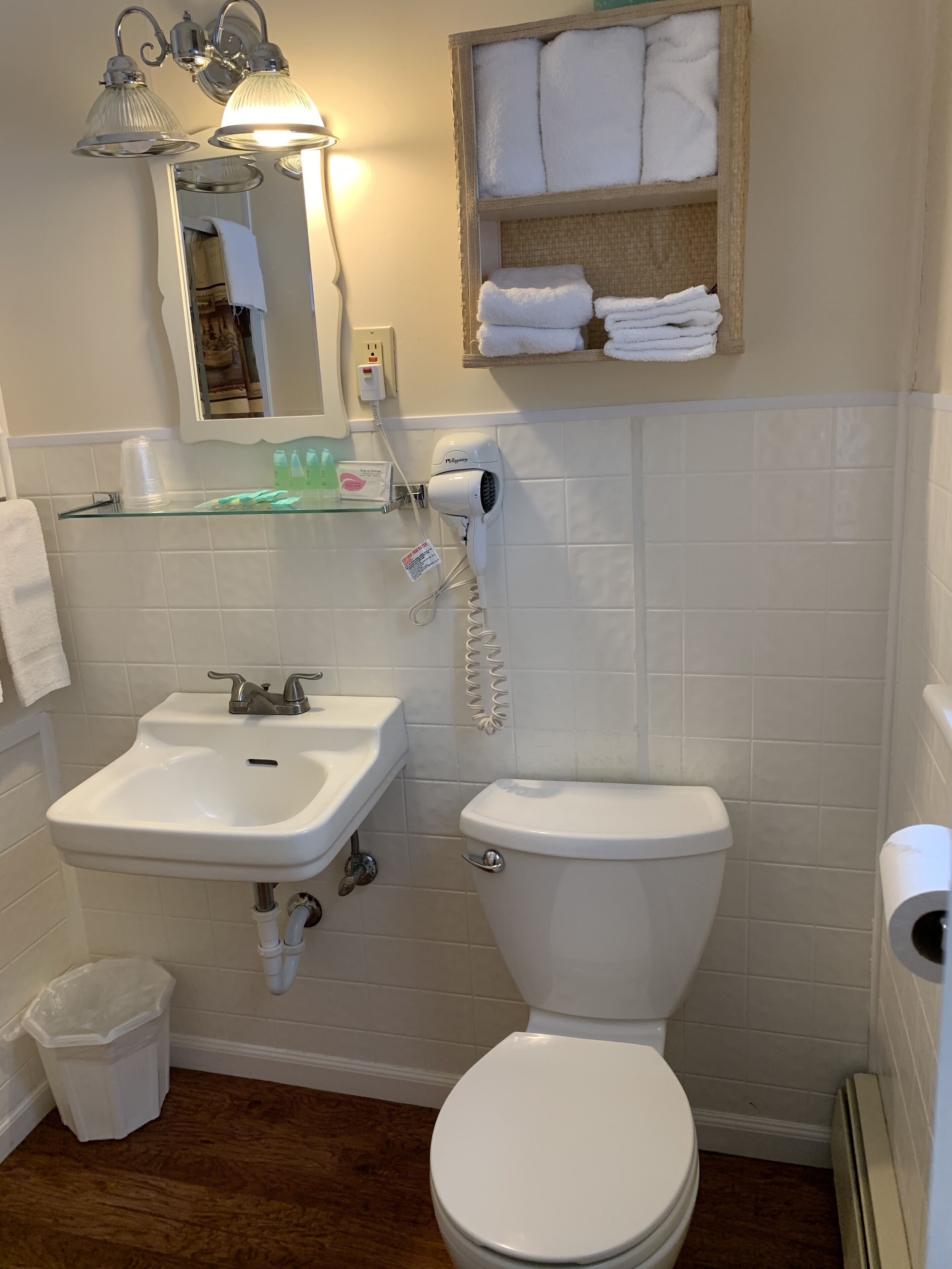 A bathroom with a white sink, toilet, and a towel rack above the mirror.