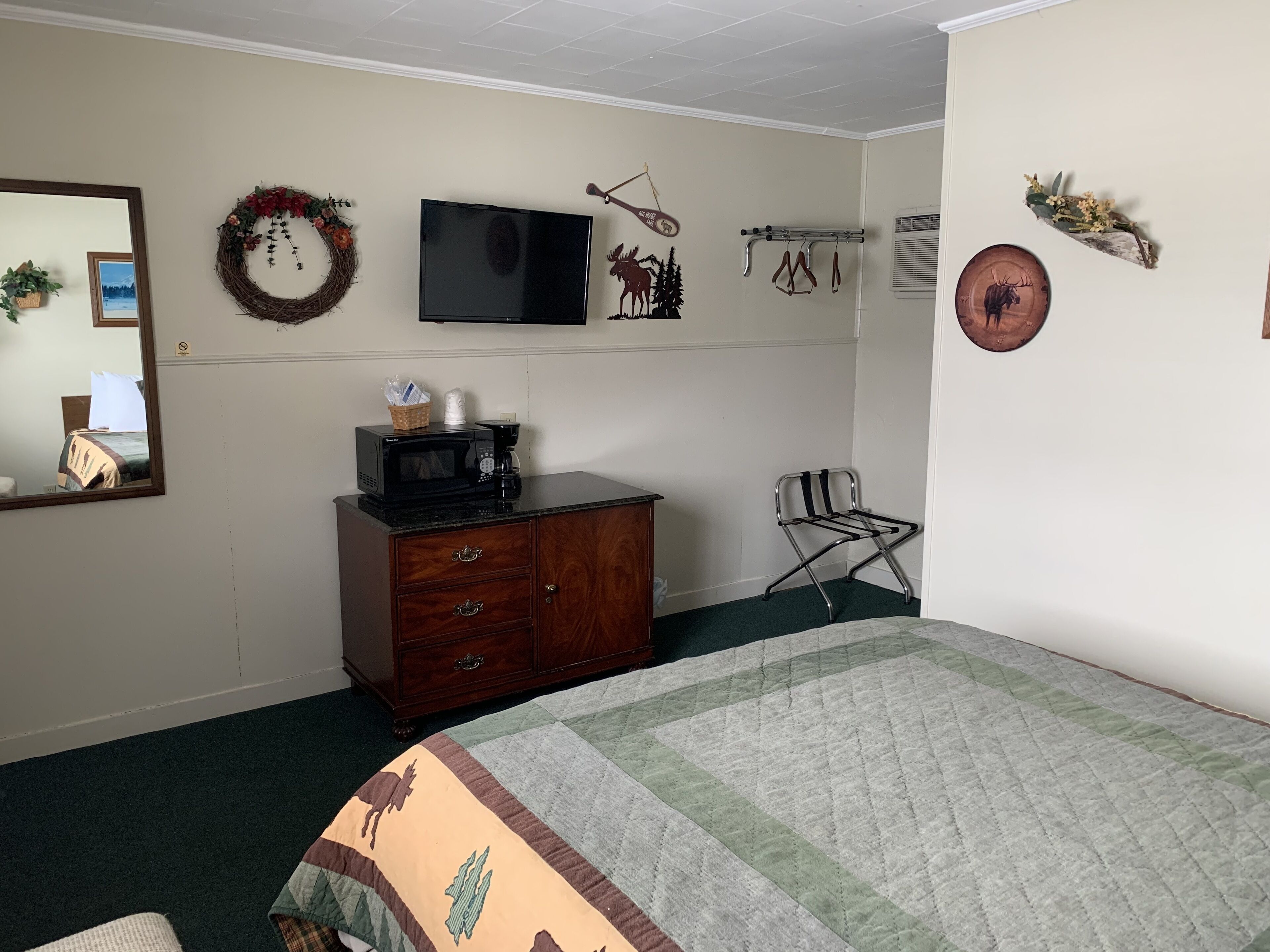 A bedroom with a bed, dresser, TV, and various wall decorations.