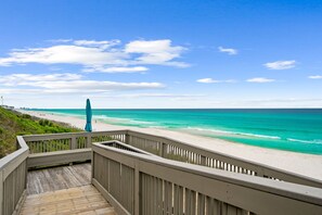 A wooden boardwalk leading to a beach with clear turquoise waters and a clear sky.