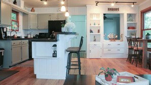 A modern kitchen with white cabinetry, a central island, and pendant lighting. - Northern Echo Cottage Swimming, Sauna, & Stunning Views.  All Season Retreat (Traverse City)