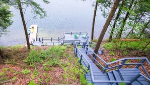 Eine Holzterrasse mit Bänken, die auf einen See blickt, umgeben von Bäumen.