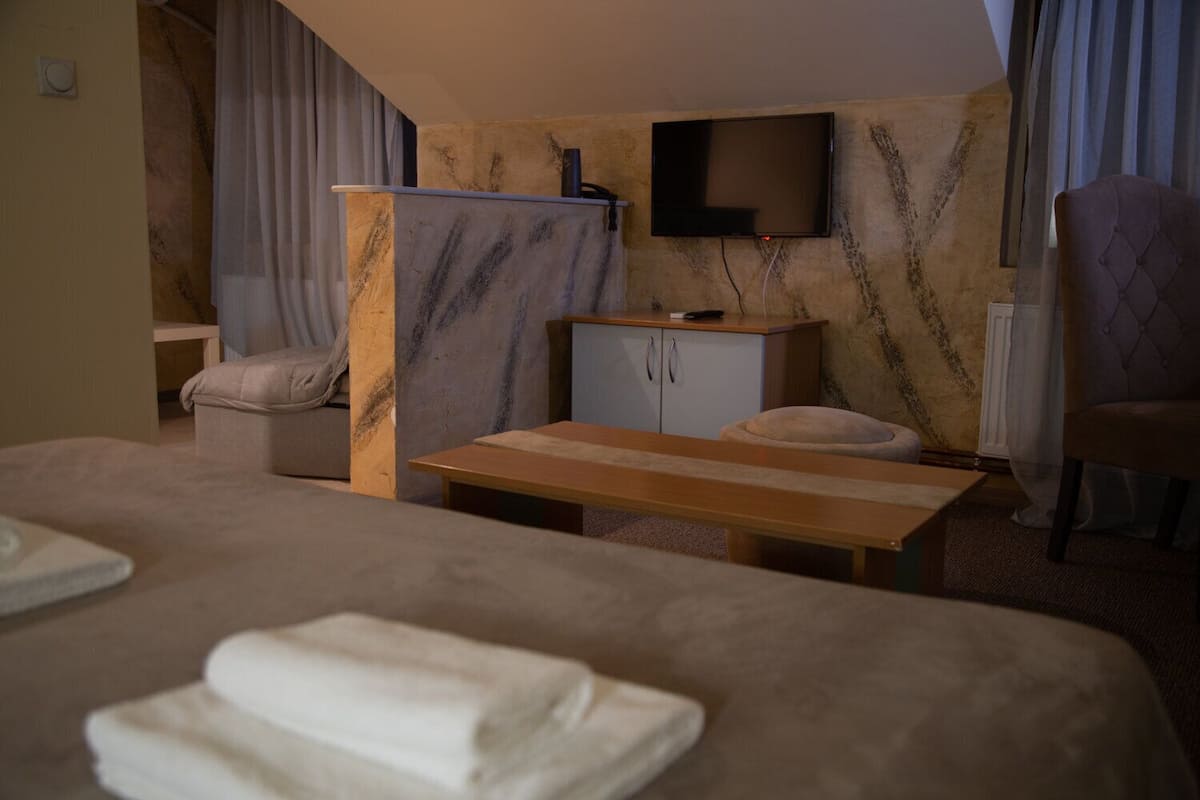 A hotel room with a bed, a desk, a chair, a TV, and a window with curtains.