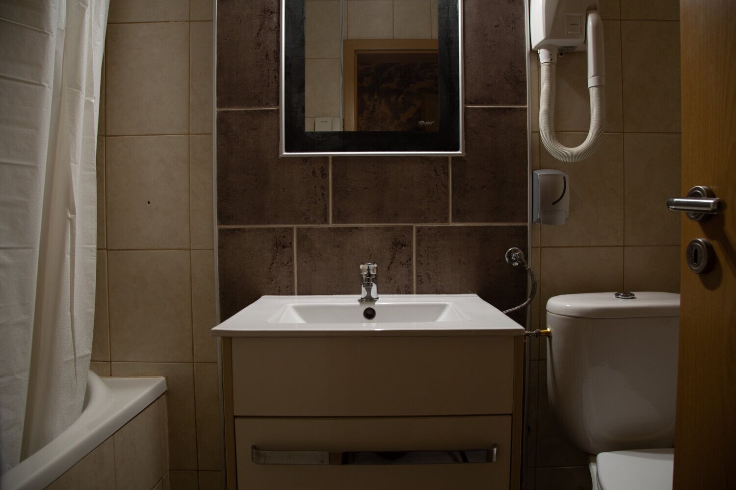 A bathroom with a white sink, a mirror, a shower, and a toilet.