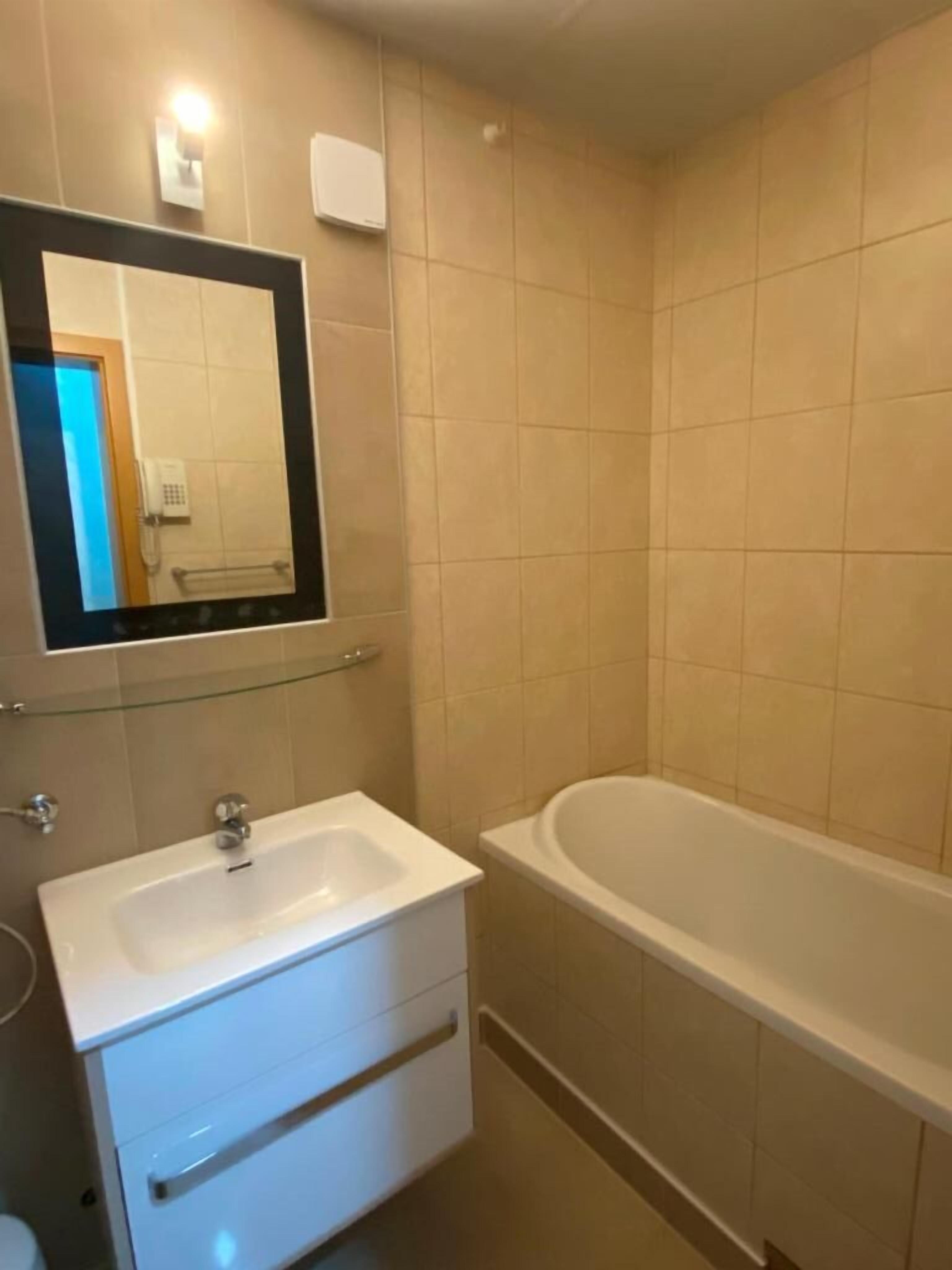 A bathroom with a white sink, a mirror, and a bathtub.