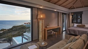 Et moderne hotelværelse med en stor balkon, et skrivebord, en seng og en sofa.