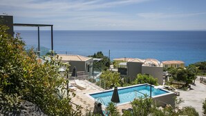 Et resort med swimmingpool, liggestole og havudsigt.