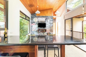 A modern kitchen with a black countertop, wooden ceiling, and a chalkboard wall with various writings.
