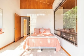 A bedroom with a bed, a window, and a door.