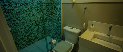 A bathroom with a mosaic-tiled shower wall, a toilet, and a sink with a mirror.
