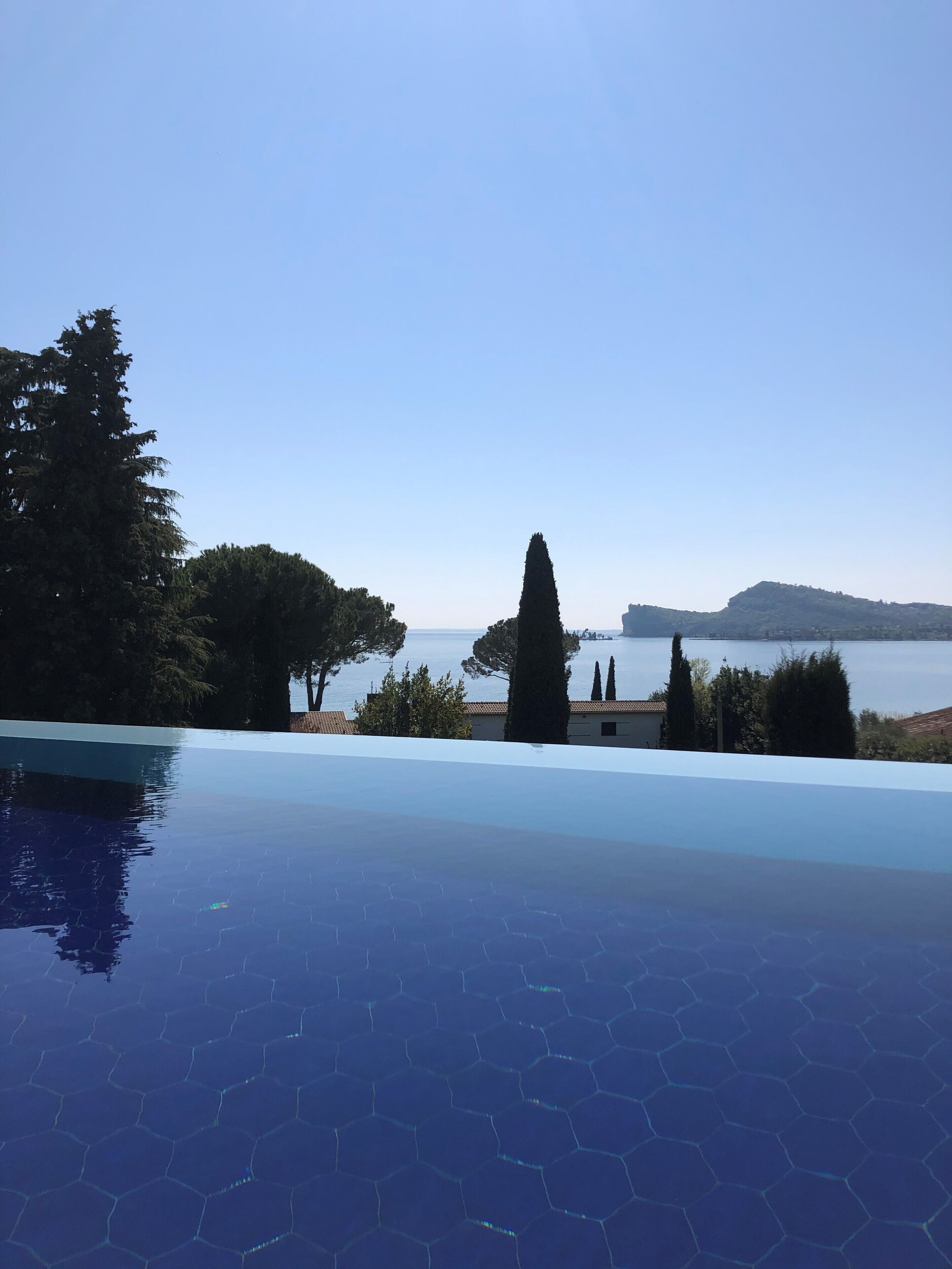 A swimming pool with a clear view of the sea and distant hills.