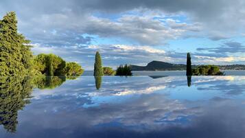 A calm lake with clear reflections of trees and a distant mountain range.