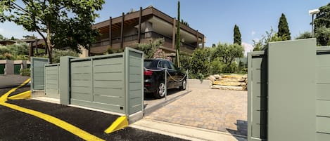 A gated parking area with a car, a building in the background, and a clear sky.