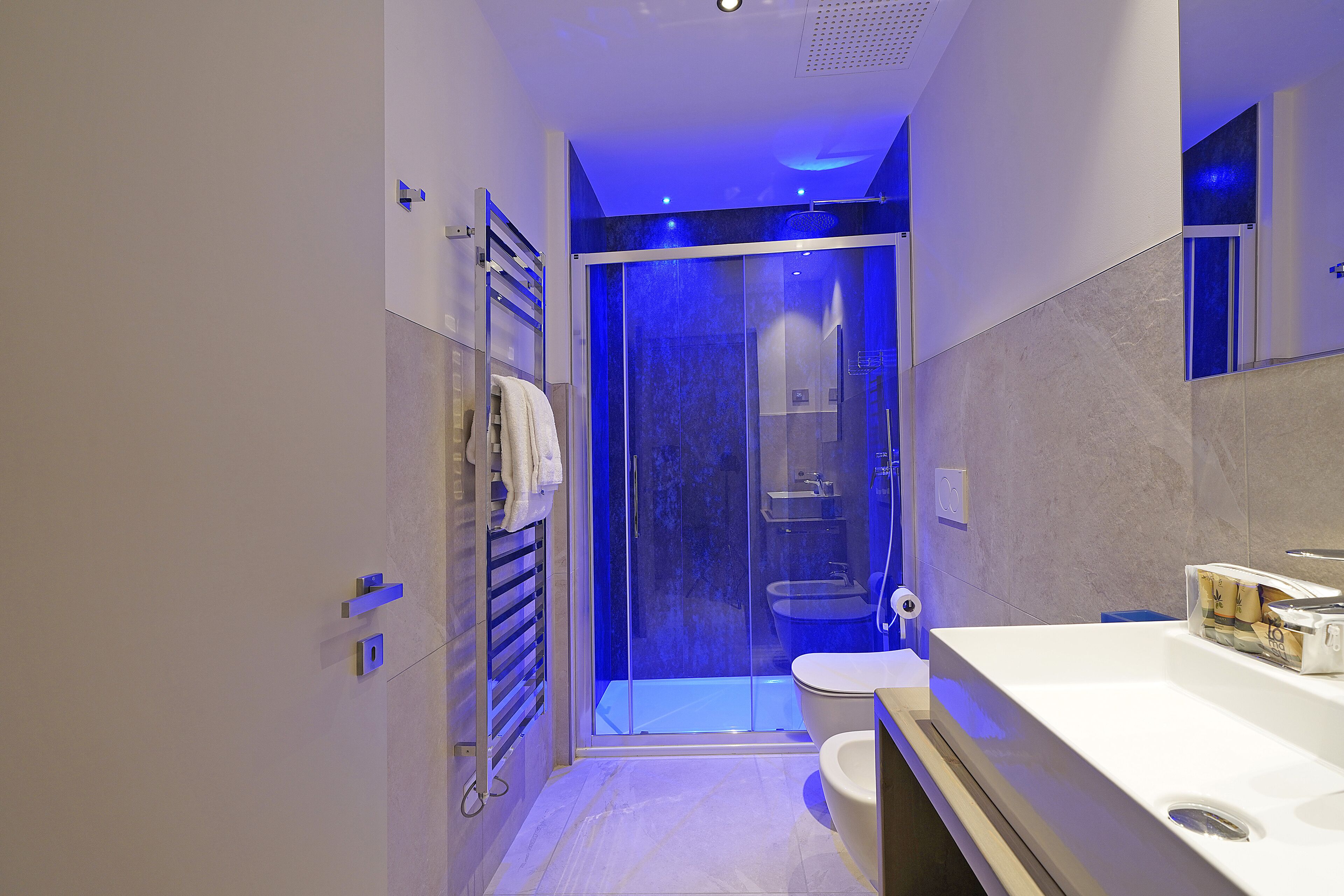 A modern bathroom with a glass shower enclosure, a white sink, and a toilet.