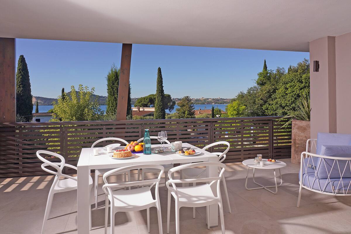 A terrace with a table set for dining, chairs, and a small round table with a chair.