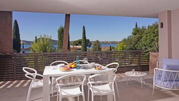 Una terrazza con tavolo apparecchiato per mangiare, sedie e un tavolino rotondo con una sedia.
