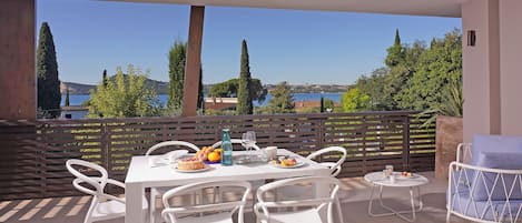 Une terrasse avec une table dressée pour le repas, des chaises et une petite table ronde avec un siège.