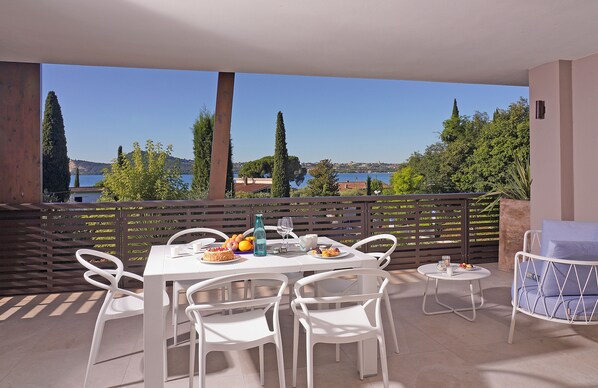 Una terraza con mesa lista para comer, sillas y una pequeña mesa redonda con una silla.