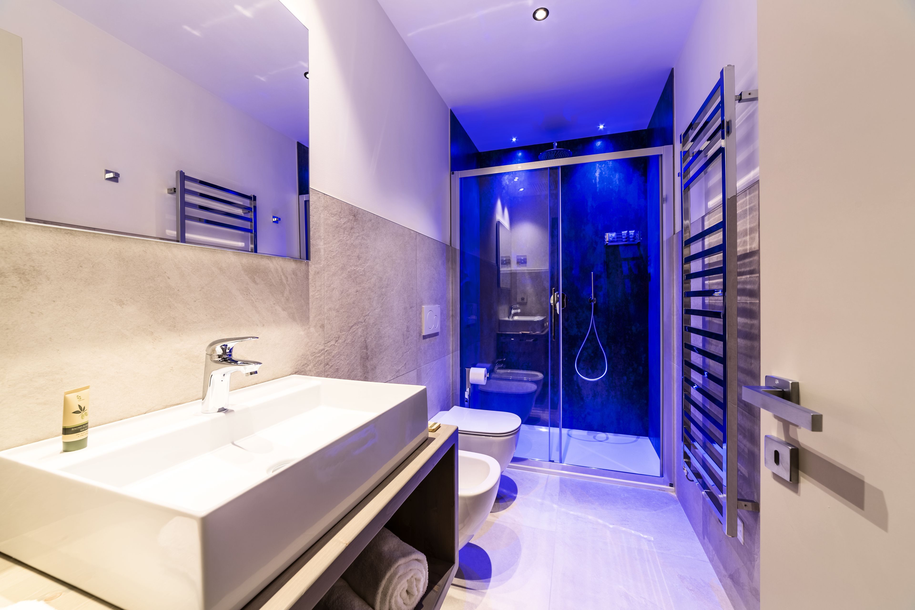 A modern bathroom with a large sink, toilet, and glass-enclosed shower.