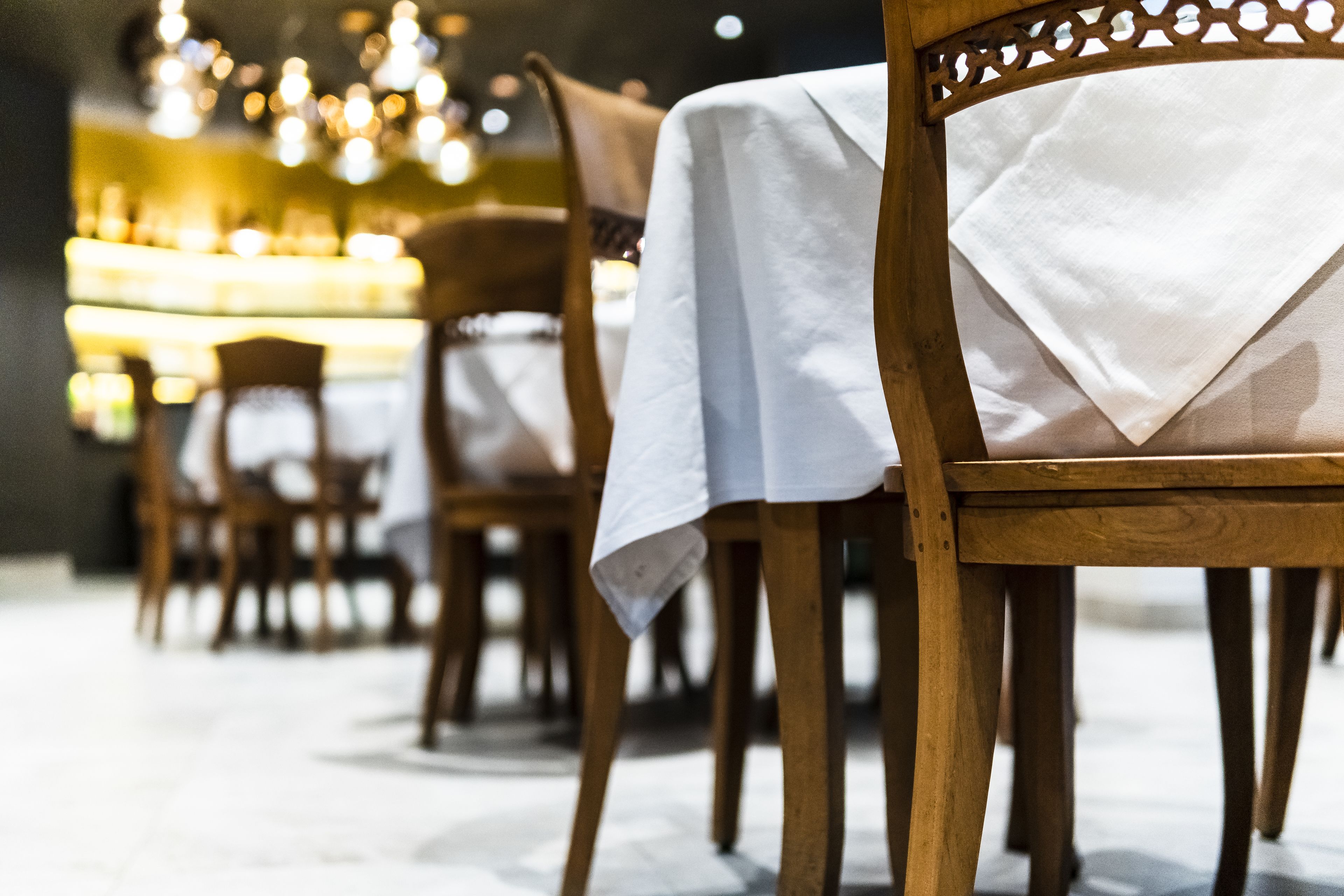 A row of wooden chairs with white tablecloths, suggesting a formal dining setting.