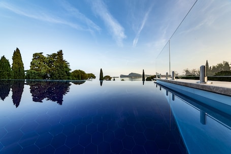 Una piscina al aire libre, sombrillas, sillones reclinables de piscina