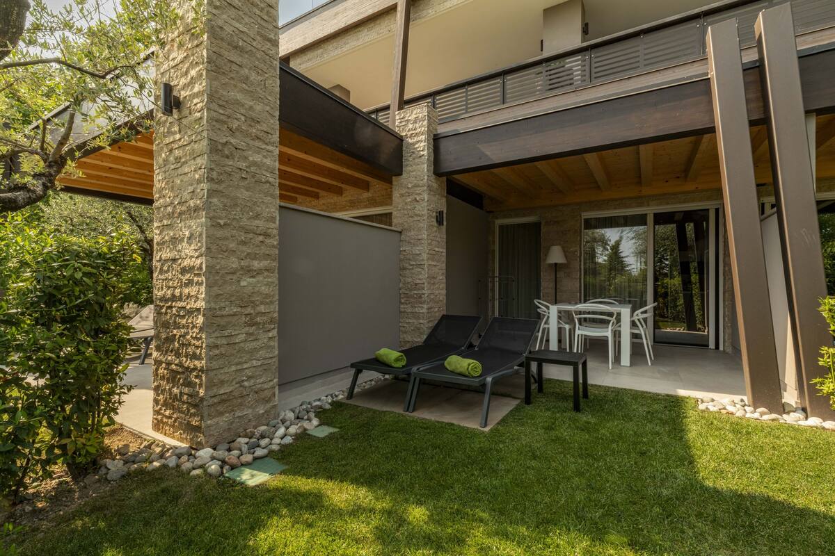 A modern outdoor patio with two lounge chairs, a table, and chairs.