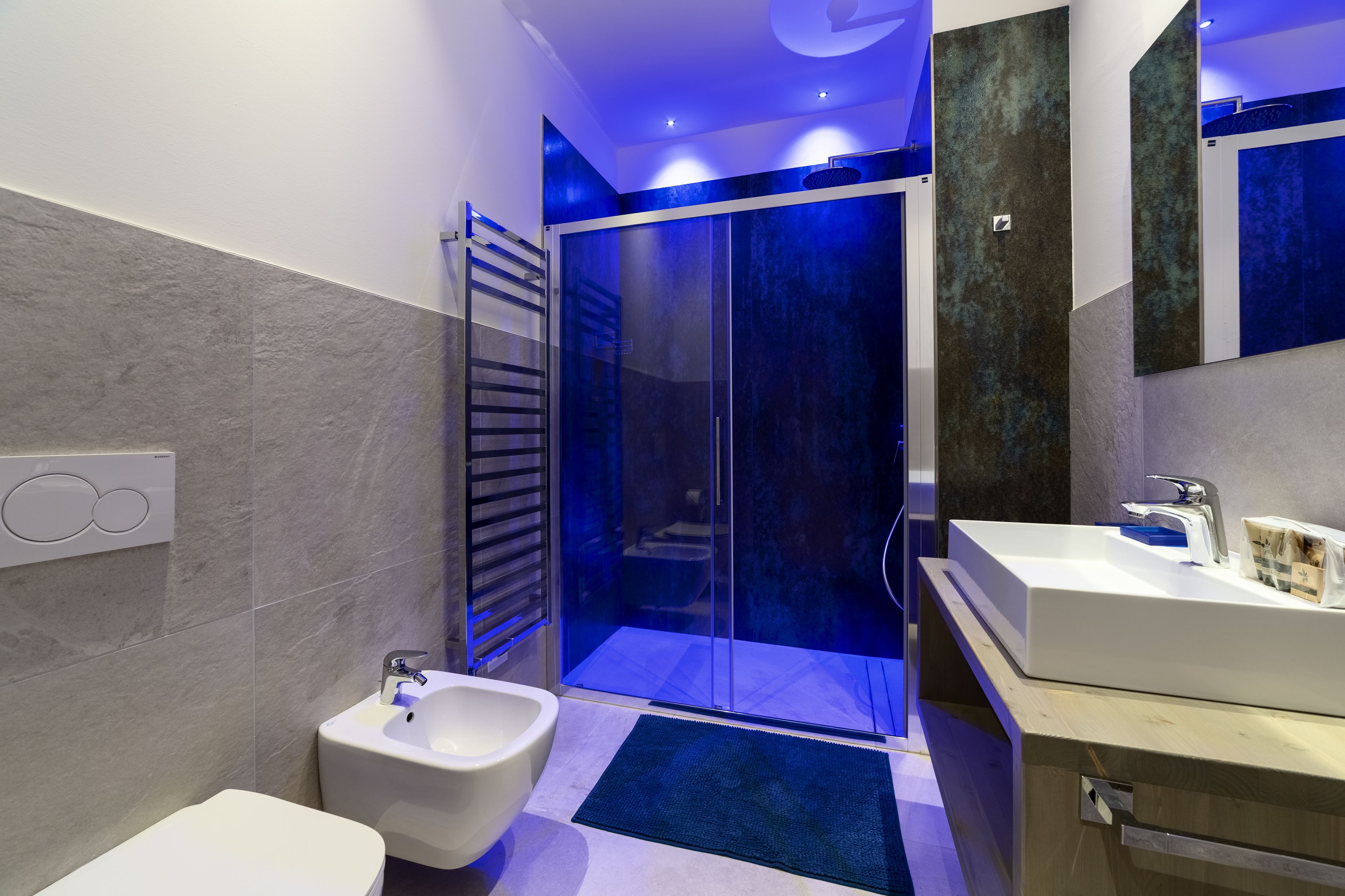 Une salle de bain moderne équipée d’un bidet, d’une douche à parois de verre et d’un meuble-lavabo avec un miroir.