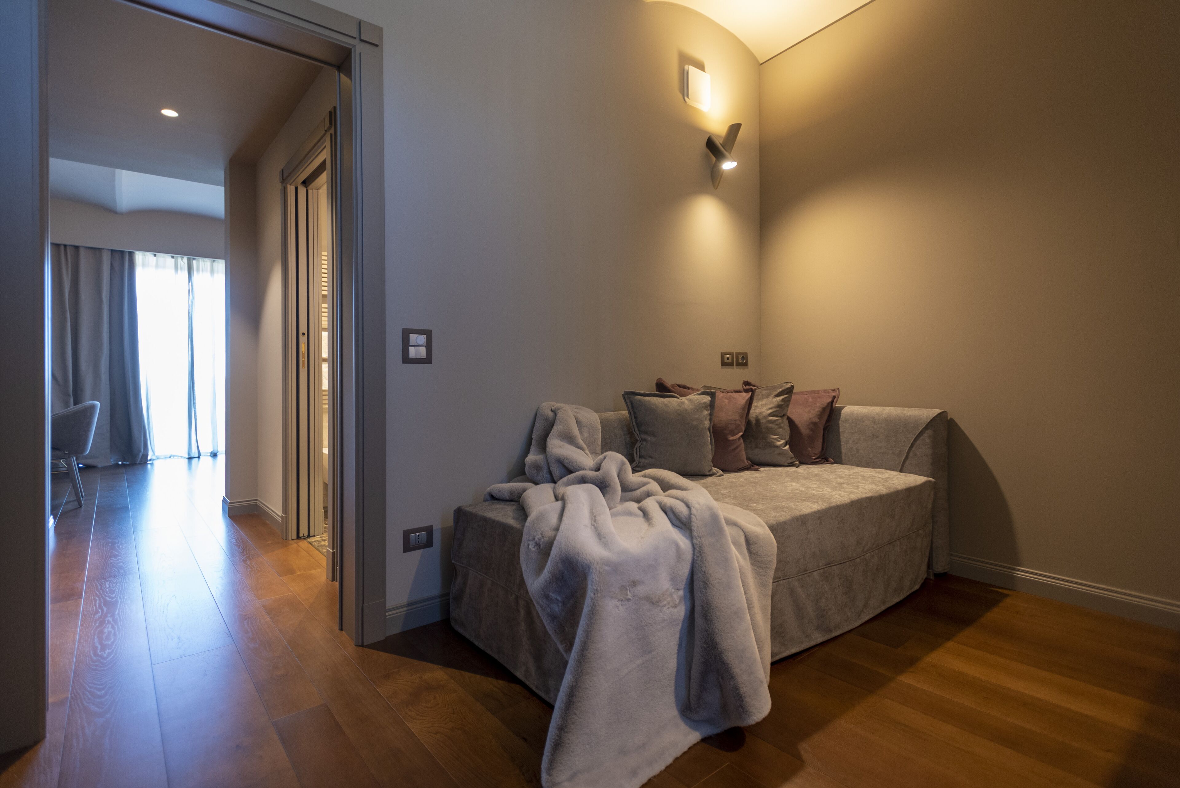 Una sala de estar acogedora con un sofá, una manta y un aplique de pared.