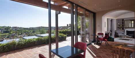 Un balcón espacioso con una mesa y sillas, con vistas a un paisaje pintoresco con edificios y vegetación.