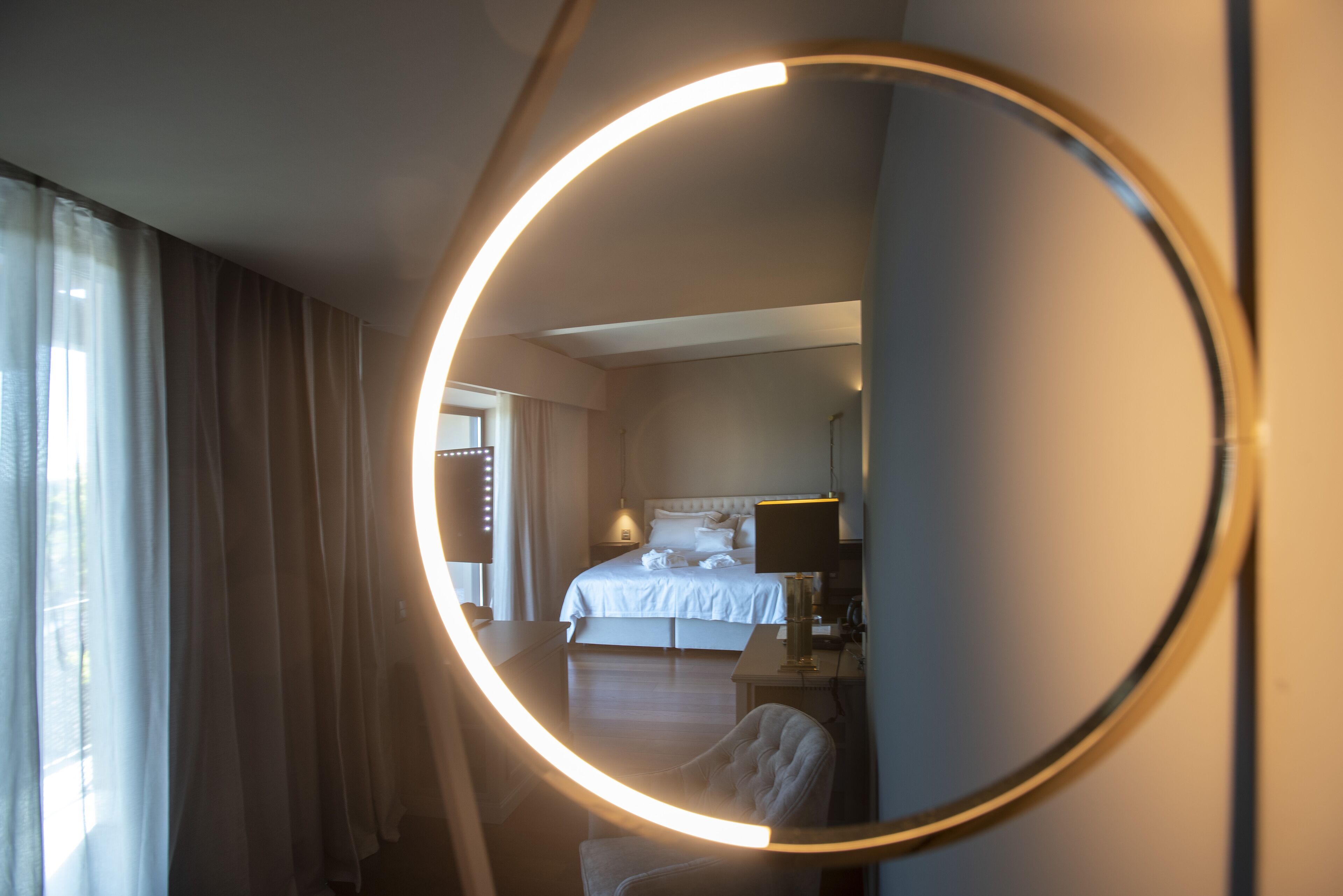 Une chambre d’hôtel avec un grand miroir, un lit, une table de chevet et une chaise.