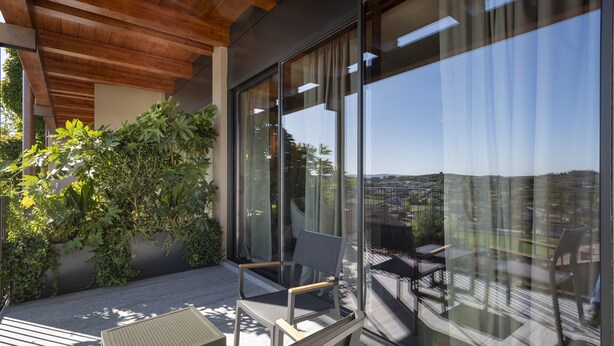 A balcony with a view of a cityscape, a wooden ceiling, and a seating area with a table and chairs.