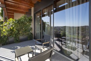 A balcony with a view of a cityscape, a wooden ceiling, and a seating area with a table and chairs. - Dimora Cordero (Priocca)