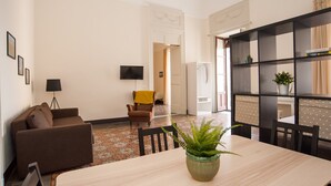 A modern living room with a sofa, a dining table, and a bookshelf.