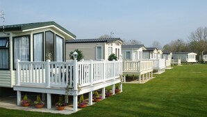 A row of mobile homes with white railings and potted plants. - Gold Standard Caravan - SOUTH VIEW PARK (Skegness)