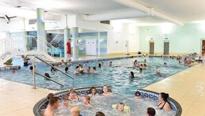 An indoor swimming pool with multiple lanes, a central staircase, and a lifeguard stand. - Gold Standard Caravan - SOUTH VIEW PARK (Skegness)