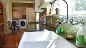 A kitchen with a sink, washing machine, and a dining area with chairs.