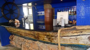 Un bar con una rueda de barco, mostrador de madera y pared de azulejos azules.