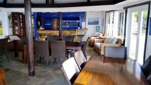 Un restaurante con zona de bar, mobiliario de mimbre y suelo de piedra.
